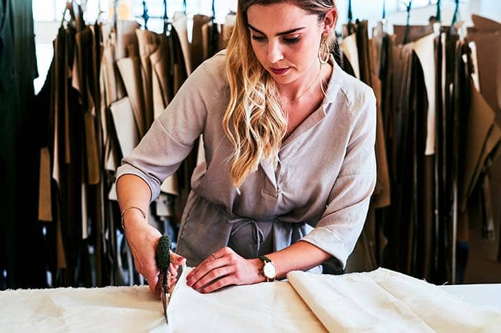 Fashion designer cutting fabric