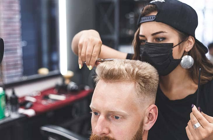 Woman hairdresser cutting mans hair