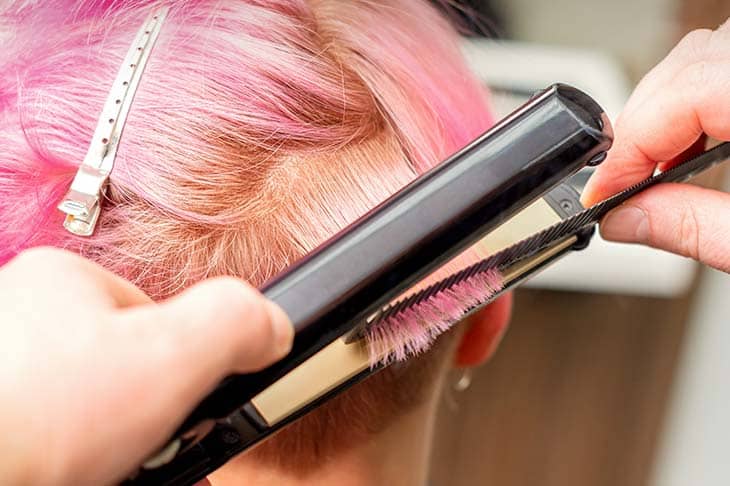 Close up hairdresser straightening iron hair