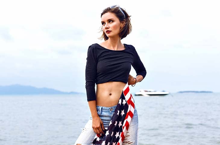 Woman posing beach holds american flag