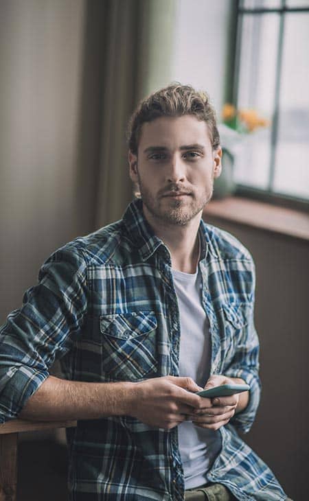 Man holds phone looking camera flannel shirt