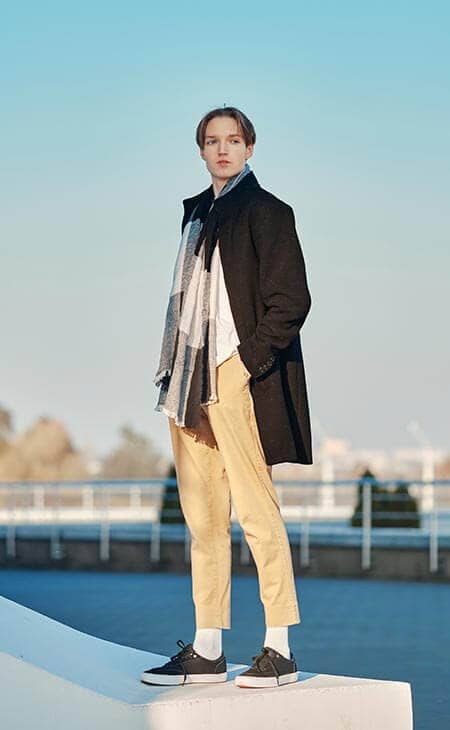 Man poses hands pockets coat scarf city