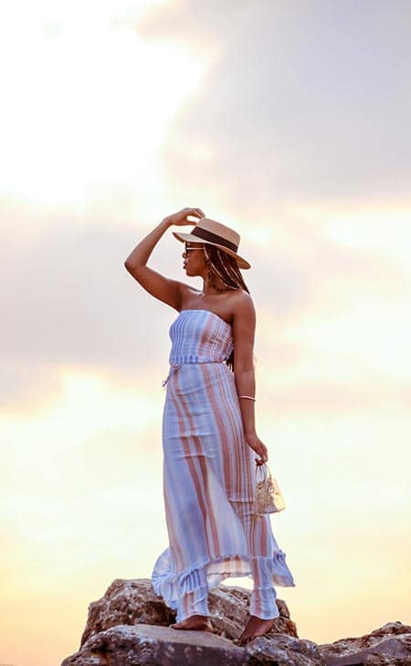 Woman posing holds hat beach dress