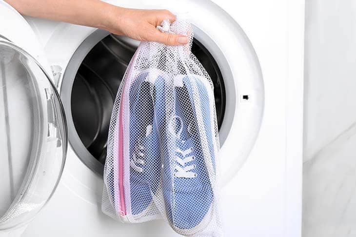 Woman hands shoes mesh laundry bag washing machine