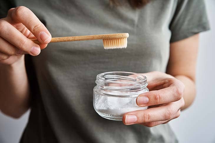 Woman holds bamboo toothbrush glass powder