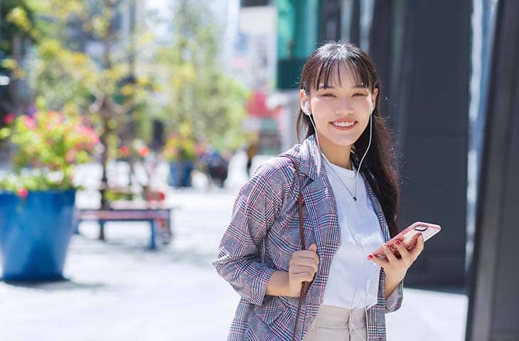 Woman smiling camera street holding phone