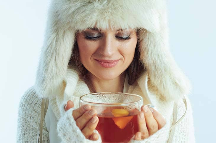 Woman fur hat holds cup tea