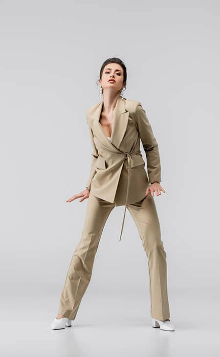 Woman in beige pantsuit looking at camera on gray
