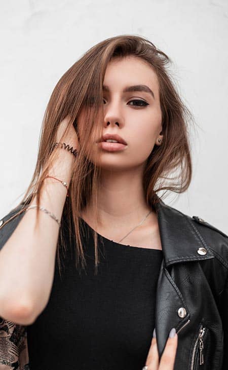 Woman posing holds hair leather jacket