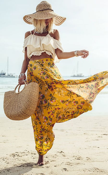 Woman walks seaside maxi skirt sunhat